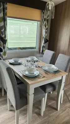 a dining room table with chairs and plates and a window at Heysham Coastal Escape Family 3-Bed Caravan in Heysham