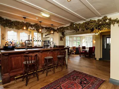 a bar in a room with a table and chairs at The Wheatsheaf at Beetham in Sandside
