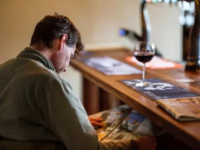 a man sitting at a table with a glass of wine at The Wheatsheaf at Beetham in Sandside