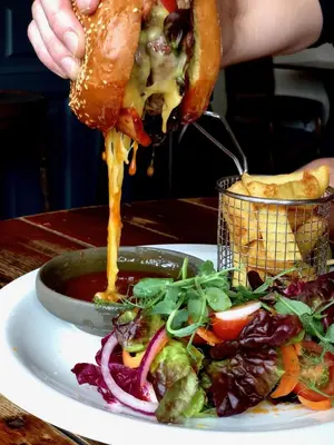 a person eating a sandwich with a salad on a plate at The Wheatsheaf at Beetham in Sandside