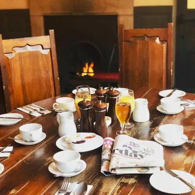 a wooden table topped with plates and cups and drinks at The Wheatsheaf at Beetham in Sandside