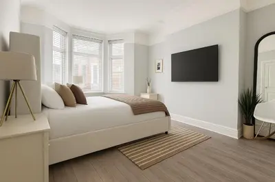 a white bedroom with a bed and a flat screen tv at Liverpool Escape - 5 min walk to LFC Stadium, Sleeps 8, free parking, newly renovated home in Liverpool