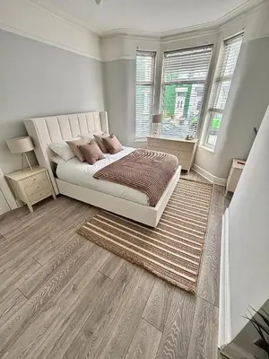 a bedroom with a large bed and two windows at Liverpool Escape - 5 min walk to LFC Stadium, Sleeps 8, free parking, newly renovated home in Liverpool