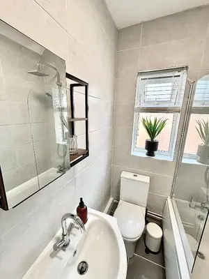 a bathroom with a sink and a toilet and a window at Liverpool Escape - 5 min walk to LFC Stadium, Sleeps 8, free parking, newly renovated home in Liverpool