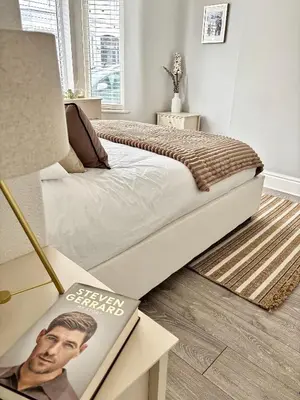 a bedroom with a bed and a book on a table at Liverpool Escape - 5 min walk to LFC Stadium, Sleeps 8, free parking, newly renovated home in Liverpool