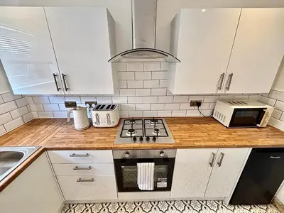 a kitchen with white cabinets and a stove top oven at Liverpool Escape - 5 min walk to LFC Stadium, Sleeps 8, free parking, newly renovated home in Liverpool