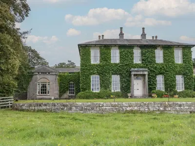 an ivy covered house with a stone wall at The Old Kitchen in Grange Over Sands