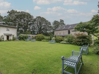 a yard with three blue benches in the grass at The Old Kitchen in Grange Over Sands