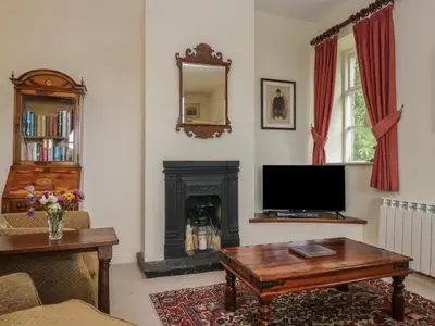a living room with a fireplace and a television at Huntsman's Cottage in Grange Over Sands