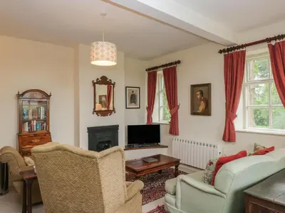 a living room with a couch and a tv at Huntsman's Cottage in Grange Over Sands