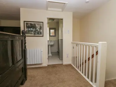 a hallway with a staircase and a sink in a house at The Laundrymaid's Cottage in Grange Over Sands