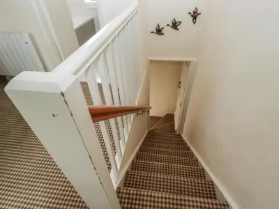 a staircase with white railings and a checkered floor at The Laundrymaid's Cottage in Grange Over Sands