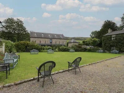 a group of chairs sitting on a lawn in front of a building at The Laundrymaid's Cottage in Grange Over Sands