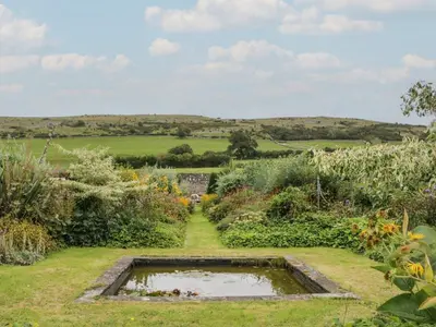 a garden with a pond in the middle at The Laundrymaid's Cottage in Grange Over Sands