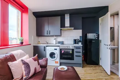a living room with a couch and a kitchen at Modern 2BR near Wigan Town Centre in Wigan
