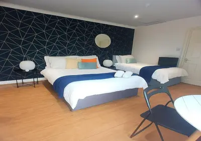 a bedroom with two beds and a chair in it at Bold Street Studio V in Liverpool