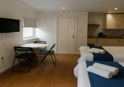 a hotel room with two beds and a table and a table and chairs at Bold Street Studio V in Liverpool
