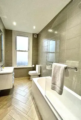 a bathroom with a tub and a toilet and a sink at Mode Apartments St Annes in Lytham St Annes