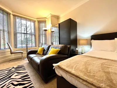 a bedroom with a bed and a couch and windows at Mode Apartments St Annes in Lytham St Annes