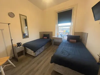 a bedroom with two beds and a mirror and a window at The Prince Alfred Rooms in Liverpool