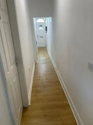 a hallway with white walls and a wooden floor at Babo accommodation in Bolton