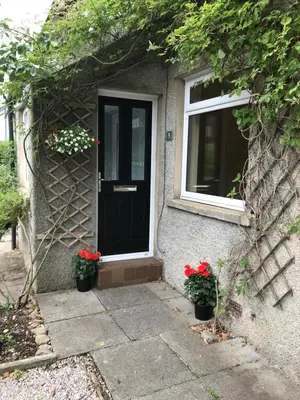 a house with a black door and two potted plants at Yealand Redmayne 3 bed Home in Beetham