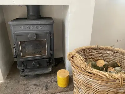 an old stove in a room with a basket of logs at Yealand Redmayne 3 bed Home in Beetham