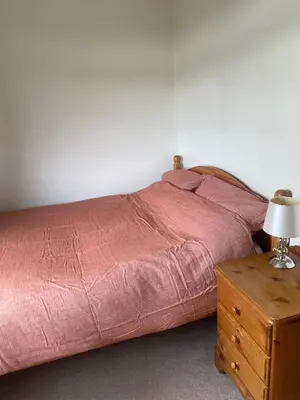 a bed with a red comforter and a table with a lamp at Yealand Redmayne 3 bed Home in Beetham