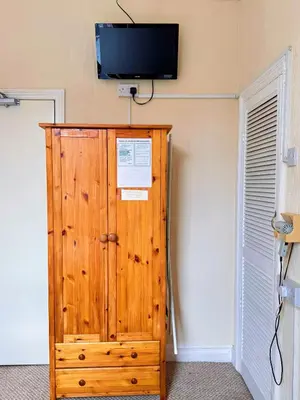 a wooden cabinet with a tv on a wall at Kendal Hotel in Blackpool