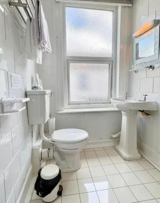 a white bathroom with a toilet and a sink at Kendal Hotel in Blackpool