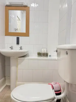 a white bathroom with a toilet and a sink at Kendal Hotel in Blackpool