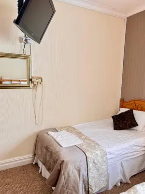 a hotel room with a bed and a flat screen tv at Kendal Hotel in Blackpool