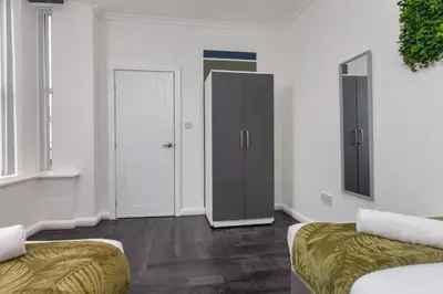 a white room with two beds and a closet at Charles Alexander Short Stay - South Pier Apartments in Blackpool