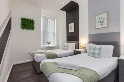 a bedroom with two beds and a window at Charles Alexander Short Stay - South Pier Apartments in Blackpool
