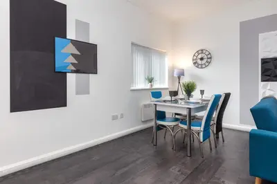 a dining room with a table and chairs and a tv at Charles Alexander Short Stay - South Pier Apartments in Blackpool