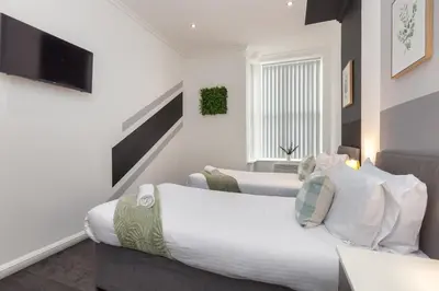 a bedroom with two beds and a television in it at Charles Alexander Short Stay - South Pier Apartments in Blackpool