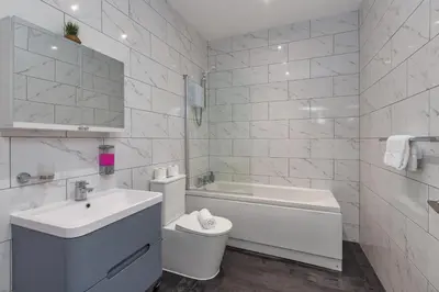 a white bathroom with a sink and a toilet at Charles Alexander Short Stay - South Pier Apartments in Blackpool
