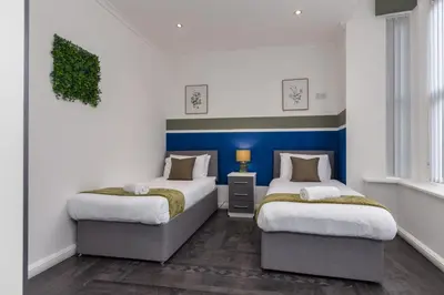 two beds in a room with blue and white walls at Charles Alexander Short Stay - South Pier Apartments in Blackpool