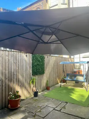 a blue umbrella on a fence with a green lawn at Valentinez Properties - Apart Hotel with a garden in Liverpool in Liverpool