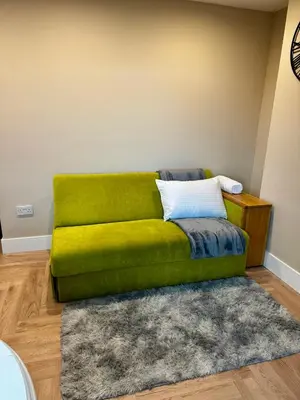 a green couch in a living room with a rug at Stylish and Bright 1 Bedroom Flat in Wallasey