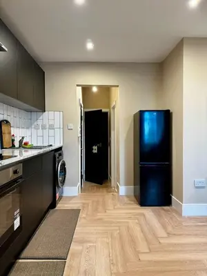a kitchen with a black refrigerator in a room at Stylish and Bright 1 Bedroom Flat in Wallasey
