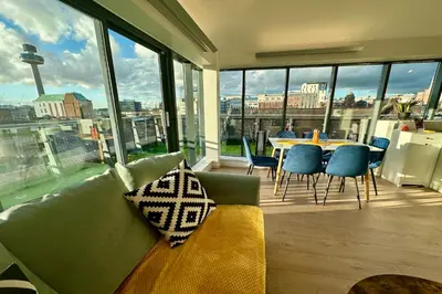 a living room with a couch and a table and chairs at City Centre Penthouse on Concert Square with City Views in Liverpool