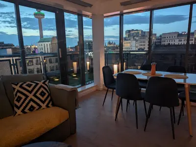 a dining room with a table and chairs and windows at City Centre Penthouse on Concert Square with City Views in Liverpool
