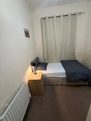 a small bedroom with a bed and a table at Room Near Anfield - Walk to the Stadium in Liverpool