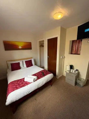 a bedroom with a large bed with red and white sheets at VERNON Hotel in Blackpool