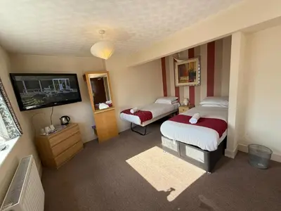 a hotel room with two beds and a flat screen tv at VERNON Hotel in Blackpool