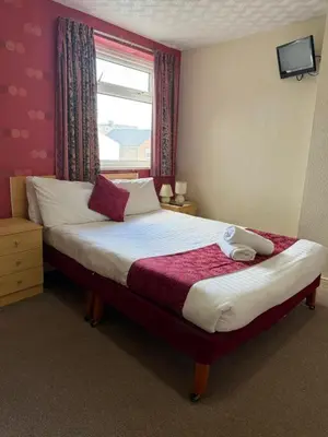 a bedroom with a large bed with a window at VERNON Hotel in Blackpool