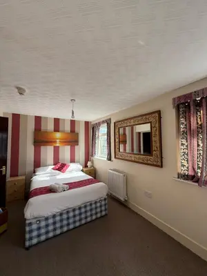 a bedroom with two beds and a mirror on the wall at VERNON Hotel in Blackpool