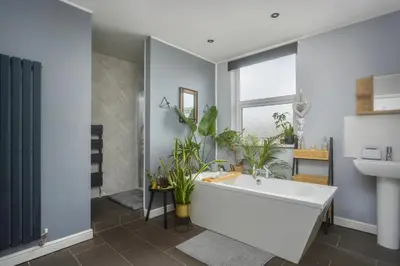 a bathroom with a large white tub and plants at Private room in a spacious home in Moreton