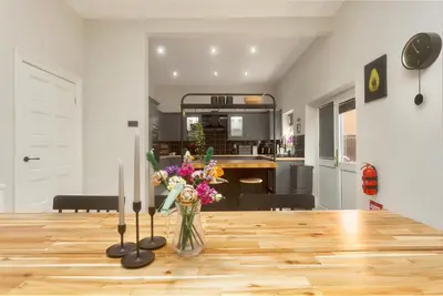 a vase of flowers on a table with two candles at Private room in a spacious home in Moreton